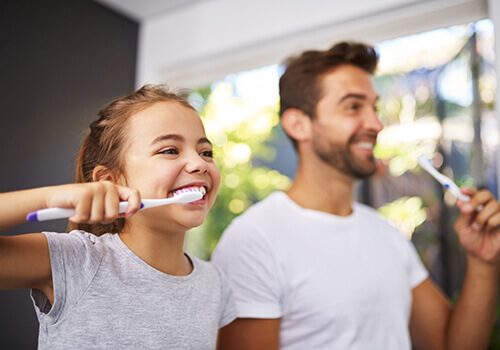 Dad teaching his daughter how to brush her teeth